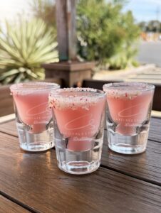 February special shot 'Mint to Be' at Carefree Spirits Distillery: three pink peppermint-rimmed shots in branded glasses on outdoor patio table