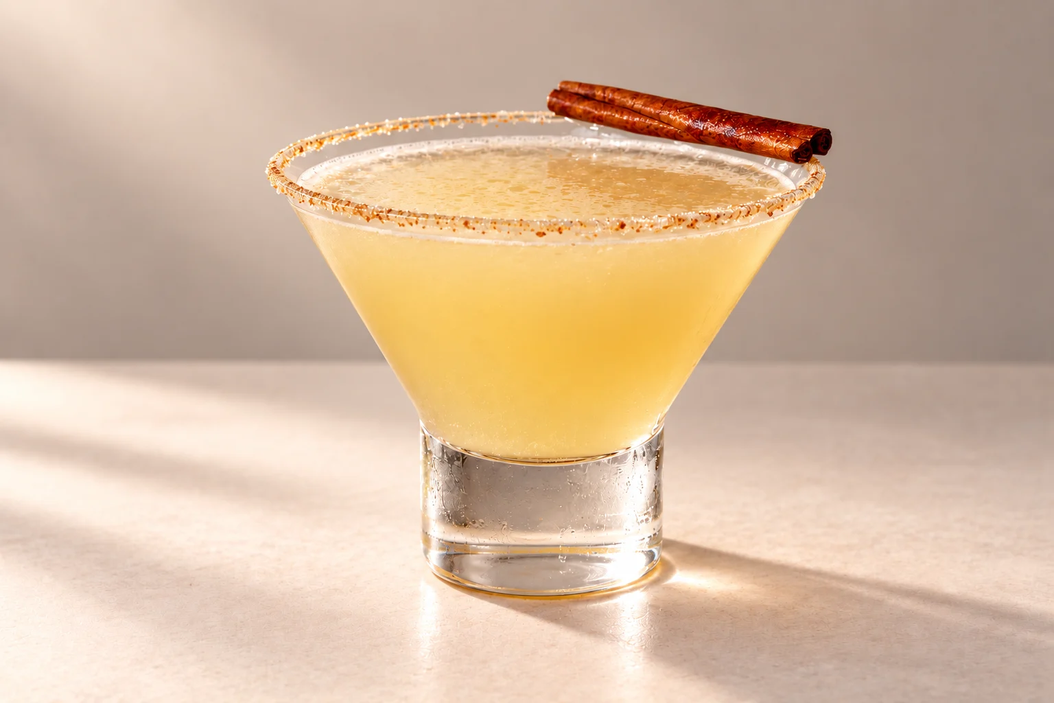 Pear Martini made with Chakra Vodka Ascension, with a brown sugar rim and cinnamon stick garnish on an ivory surface.