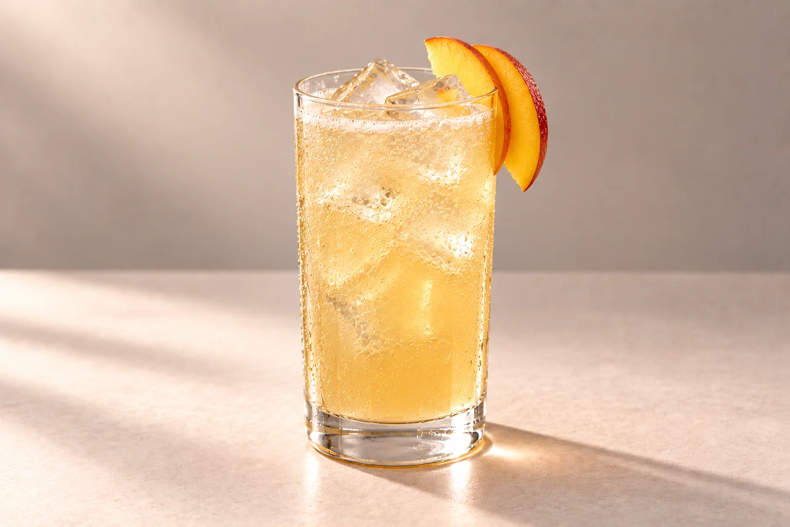 Peach & Hibiscus Fizz made with Peach & Hibiscus Chakra Vodka, served over ice in a highball glass with peach slices on an ivory surface.