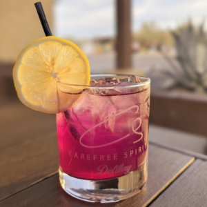 Vibrant purple pink Prickly Peach cocktail with lemon slice garnish at Carefree Spirit Distillery